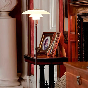 Modern floor lamp with a wide, flat shade illuminating a side table with framed photographs.