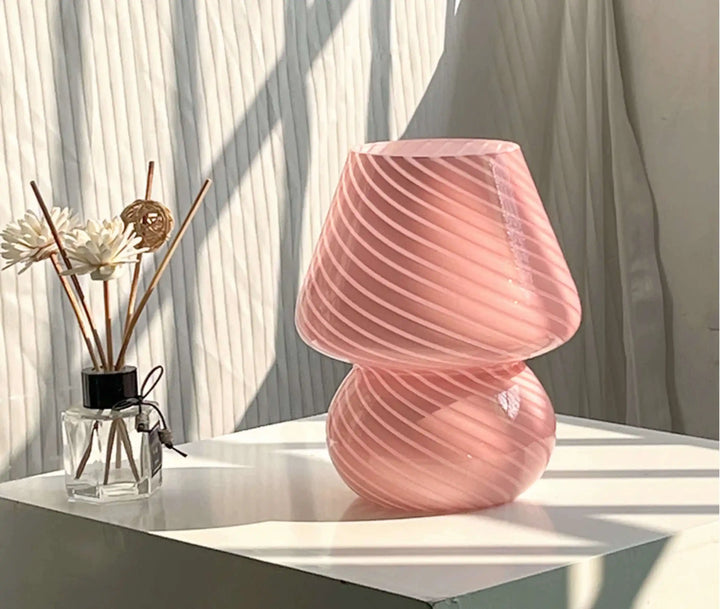 Pink glass table lamp with a swirled, mushroom-shaped design.