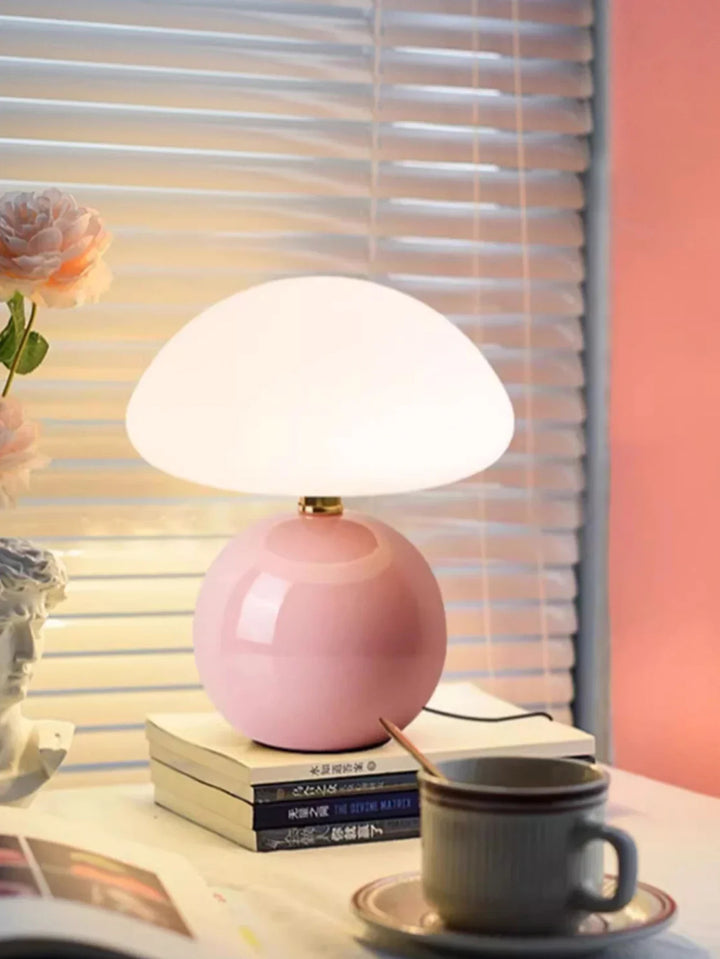 Pink mushroom-shaped table lamp with a round base and domed white shade.