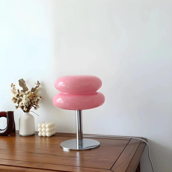 Pink, rounded stool or chair with a metallic pedestal base.