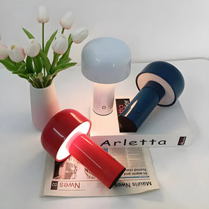 Collection of modern table lamps in various colors alongside a vase of white tulips.