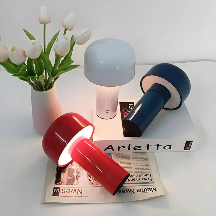 Collection of portable LED lamps in different colors alongside a vase of white tulips.