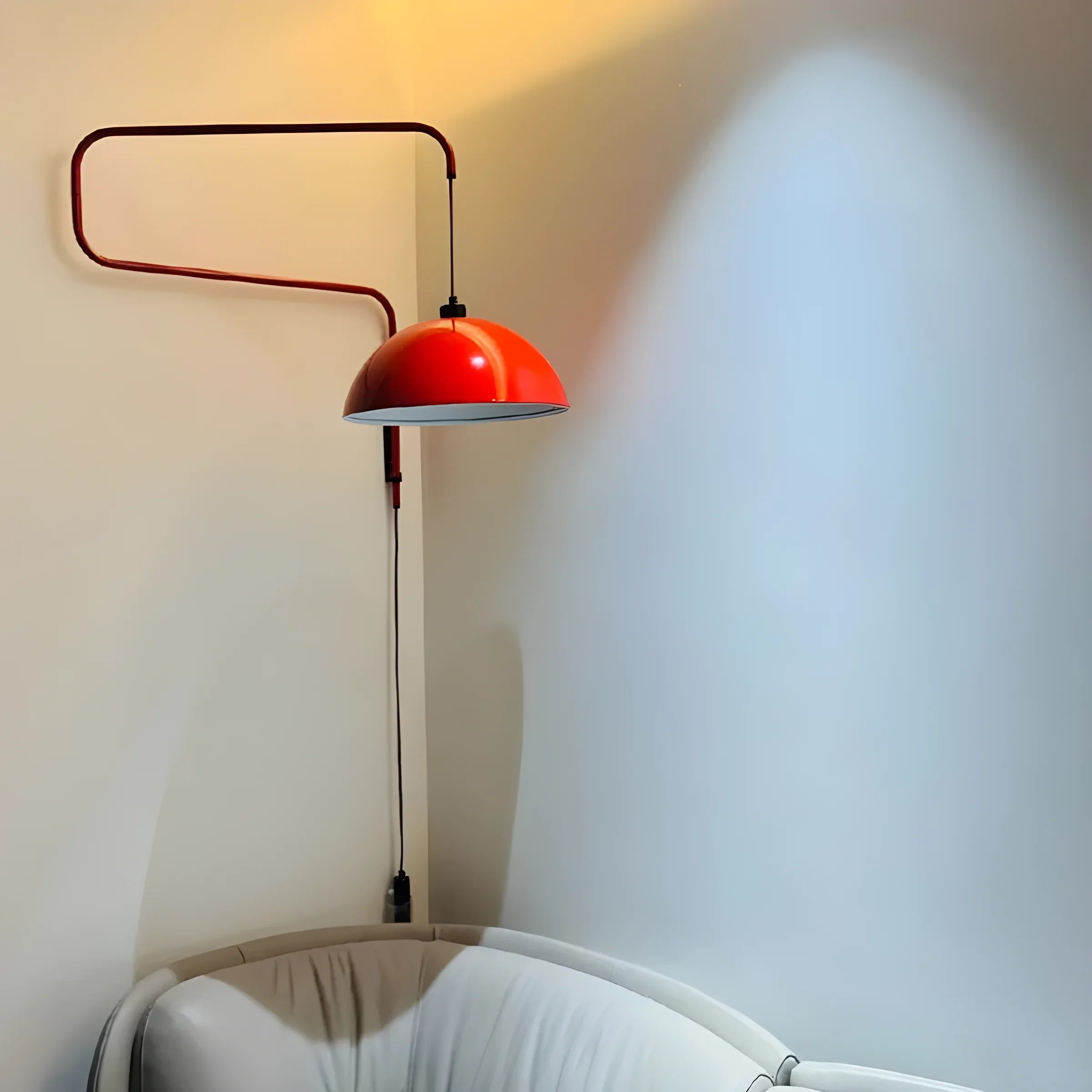 Red dome-shaped lamp with a curved arm mounted on a wall.