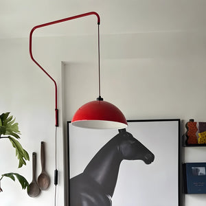 Red dome-shaped pendant lamp with an adjustable arm mounted on the wall.