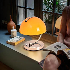 Retro-style table lamp with an orange dome-shaped shade on a curved metal base.