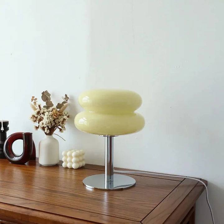 Pale yellow table lamp with a rounded, mushroom-shaped shade on a metal base.